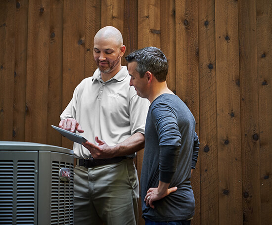 HVAC technician explaining a newly installed Lennox heat pump to the homeowner