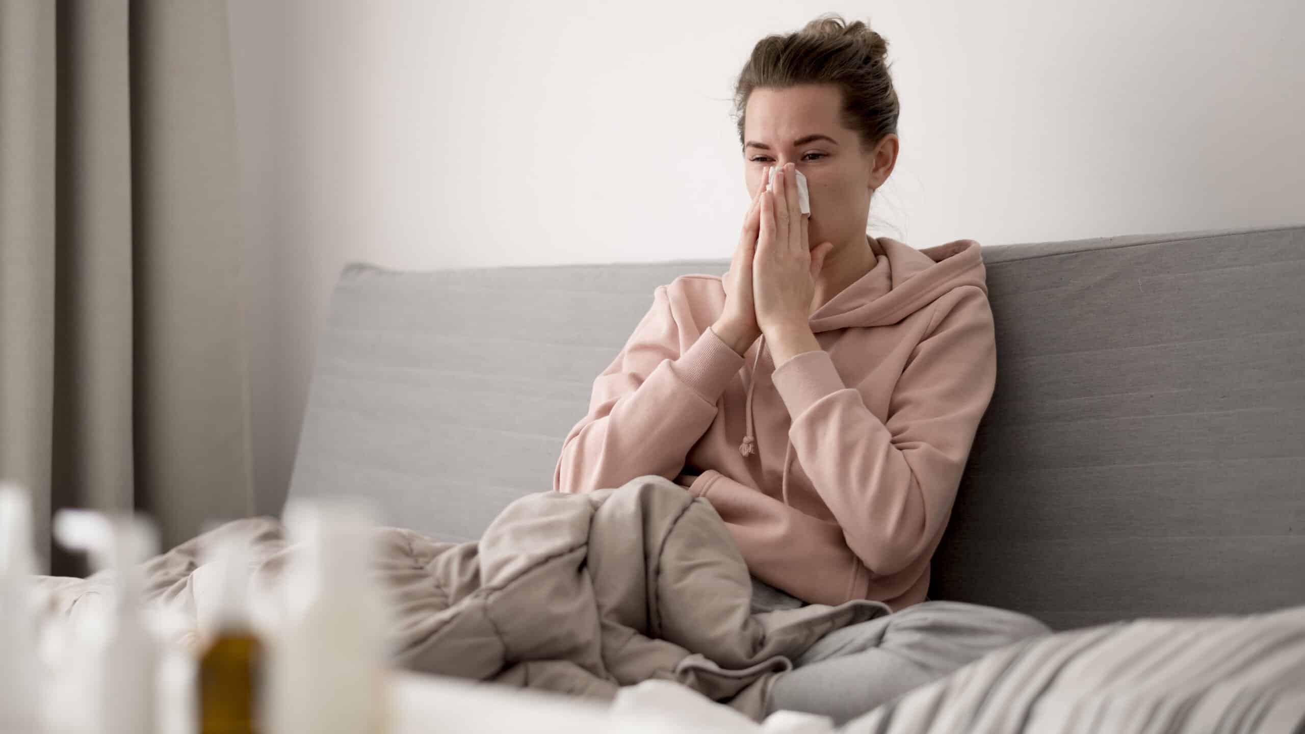 woman indoors blowing her nose due to seasonal allergies in Guelph, ON